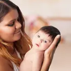 Mum holding newborn during daily routine, supporting newborn care and daily rhythm advice