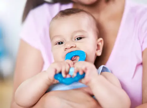 Baby chewing teething ring demonstrating teething signs and soothing tips